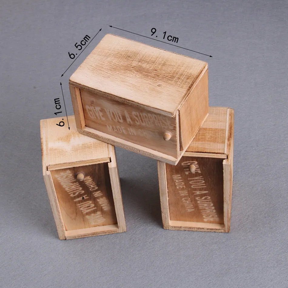 A closed wooden prank scare box measuring 9.1 cm, with a random lifelike animal inside ready to jump out.