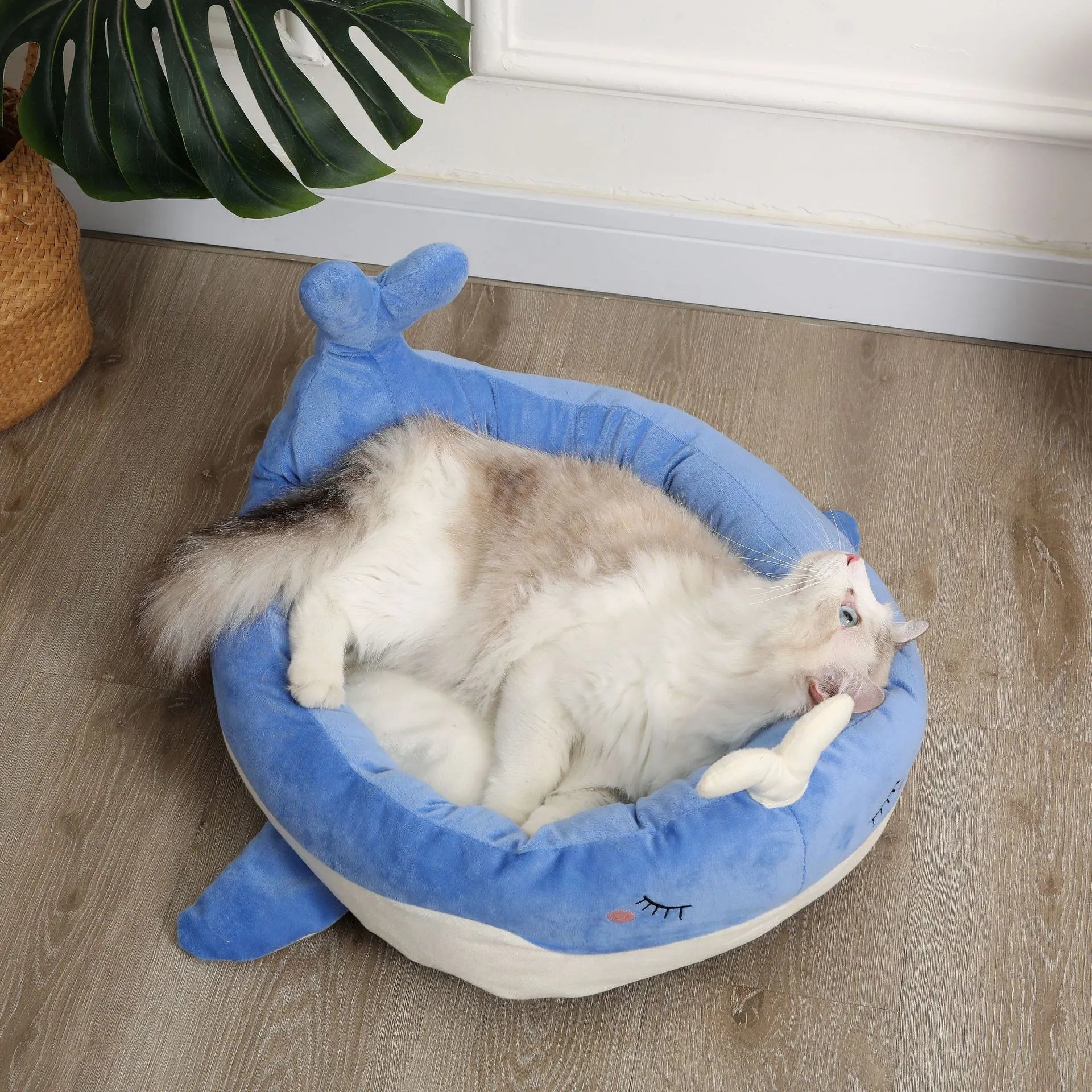 Blue duck-shaped fluffy pet bed for small dogs and cats on a wooden floor.