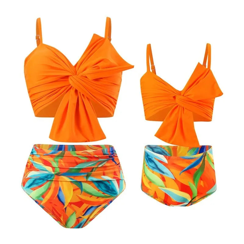 Women's orange nylon bikini set with large white bow print, showing top and swim trunks.