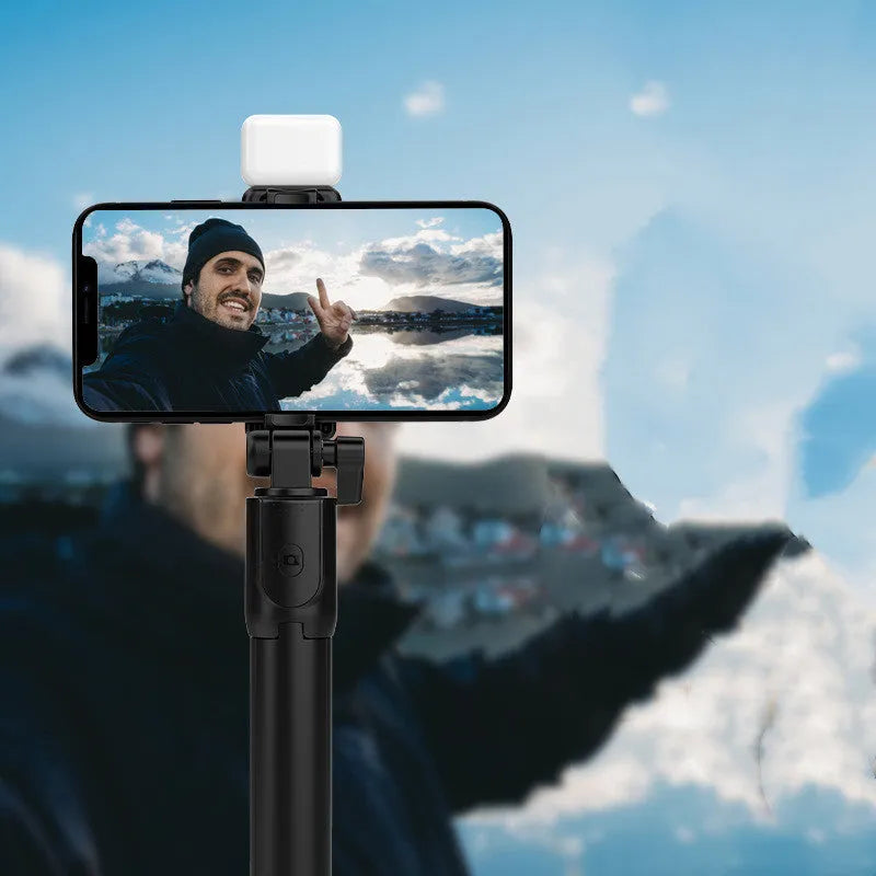 Aluminium alloy Bluetooth selfie stick with integrated tripod legs and 360-degree rotating phone holder in black.