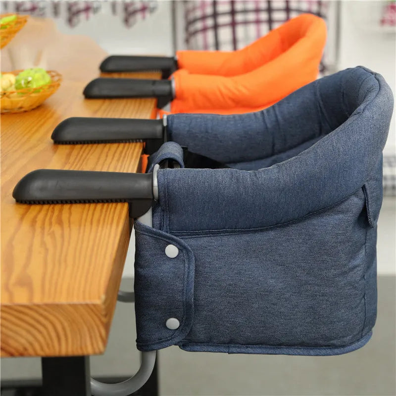 Portable baby dining seat with safety belt in blue, grey or red colours folded to show compact 42x36x7cm size