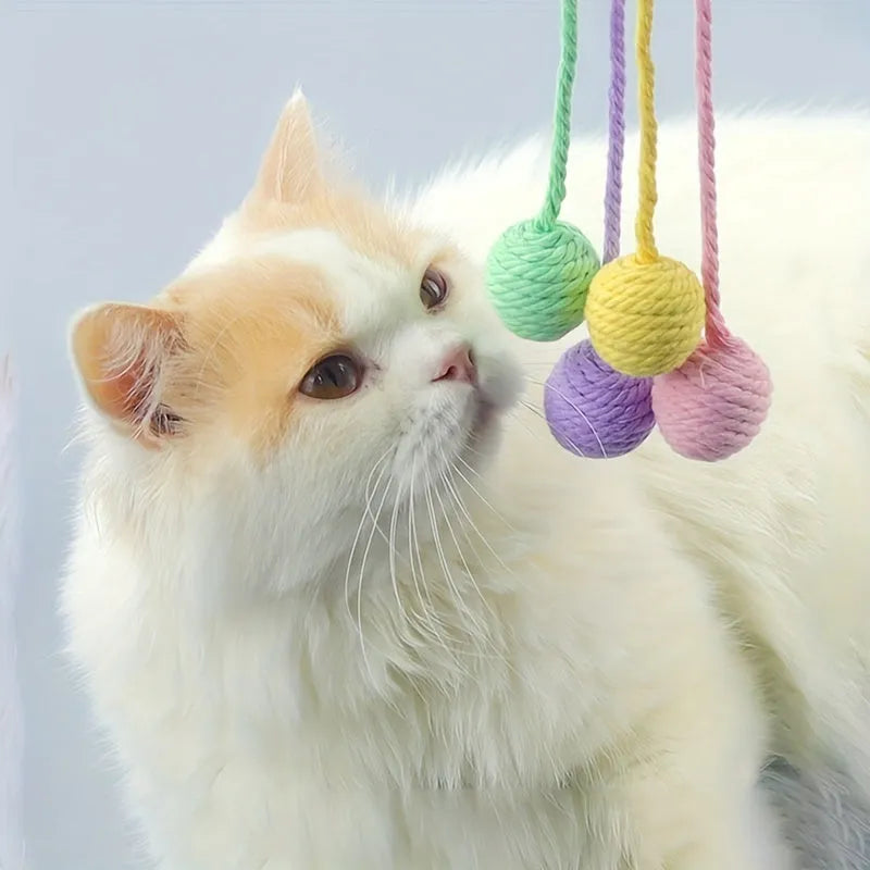 Colourful cat toy ball with attached rope and internal bell, shown in green, pink, purple, and yellow variants.