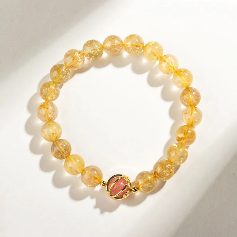 Citrine and gold rutilated quartz bracelet with diamond-cut beads in 6mm or 8mm size on a wrist.