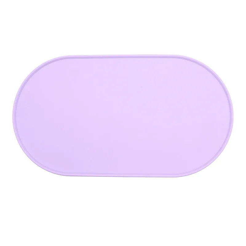 Silicone waterproof cat feeding placemat in beige colour on a floor next to a food bowl.
