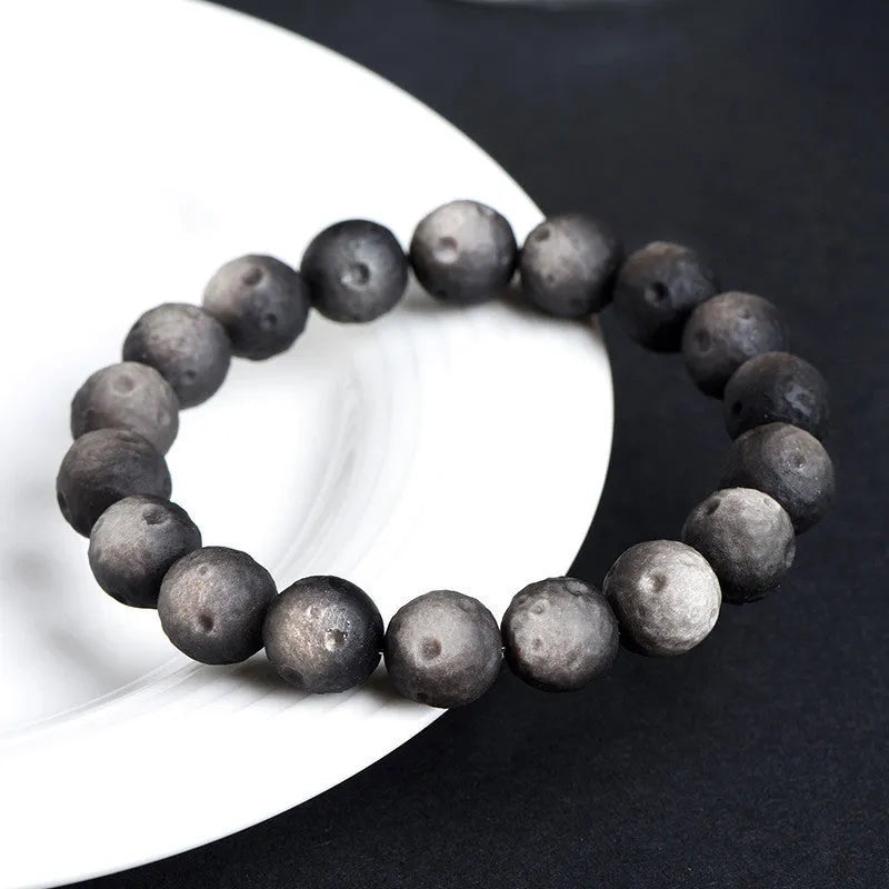 Natural obsidian crater ball bracelet with textured beads in gold or silver stone finish on a wrist.