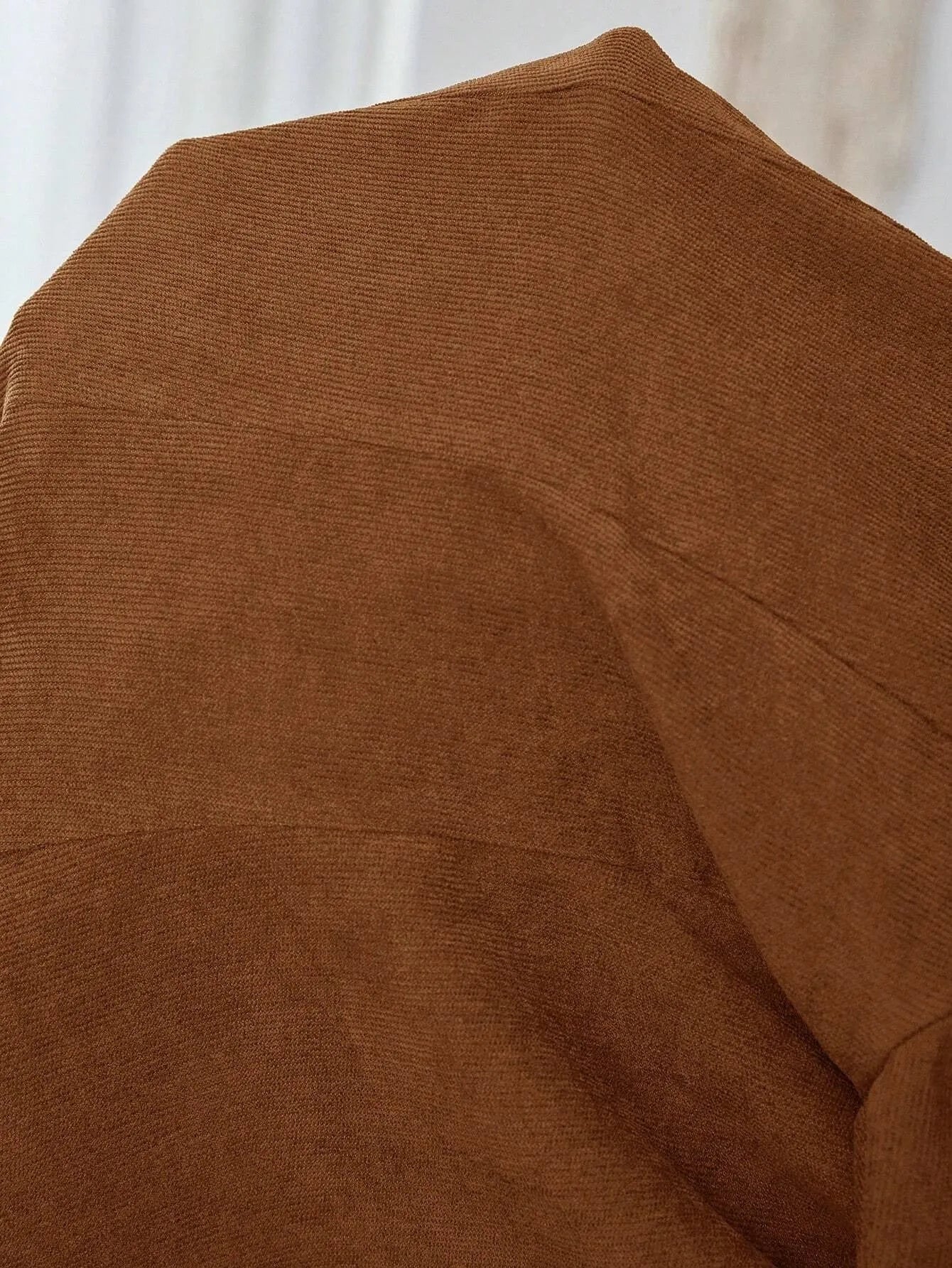 A brown men's single-breasted lapel suit coat with long sleeves on a hanger.