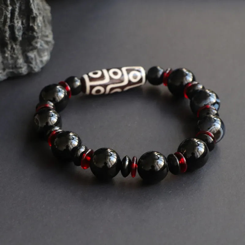 Hand-woven black agate Dzi bead bracelet with chalcedony detail on a wrist.