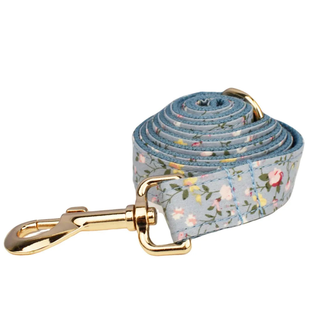 Blue floral patterned adjustable dog collar with matching leash, bow, and vest on a white background.