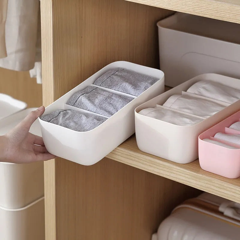 PP plastic socks and underwear storage box with grid compartments in apricot colour on a desktop