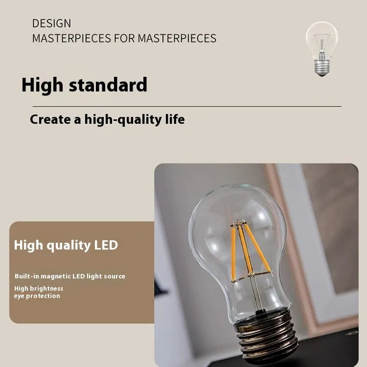 Creative small iron suspension bulb night lamp on a black woodgrain base for desktop decoration.