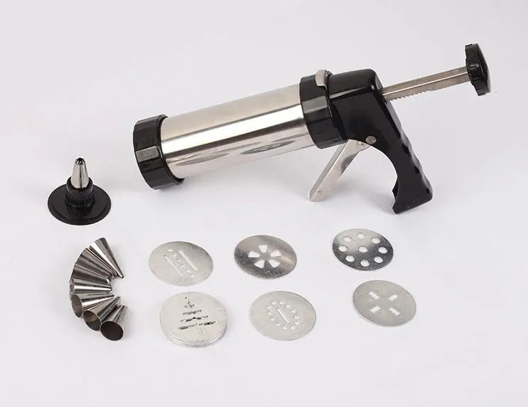 Stainless steel biscuit press machine with assortment of cookie moulds and piping nozzles on a kitchen worktop