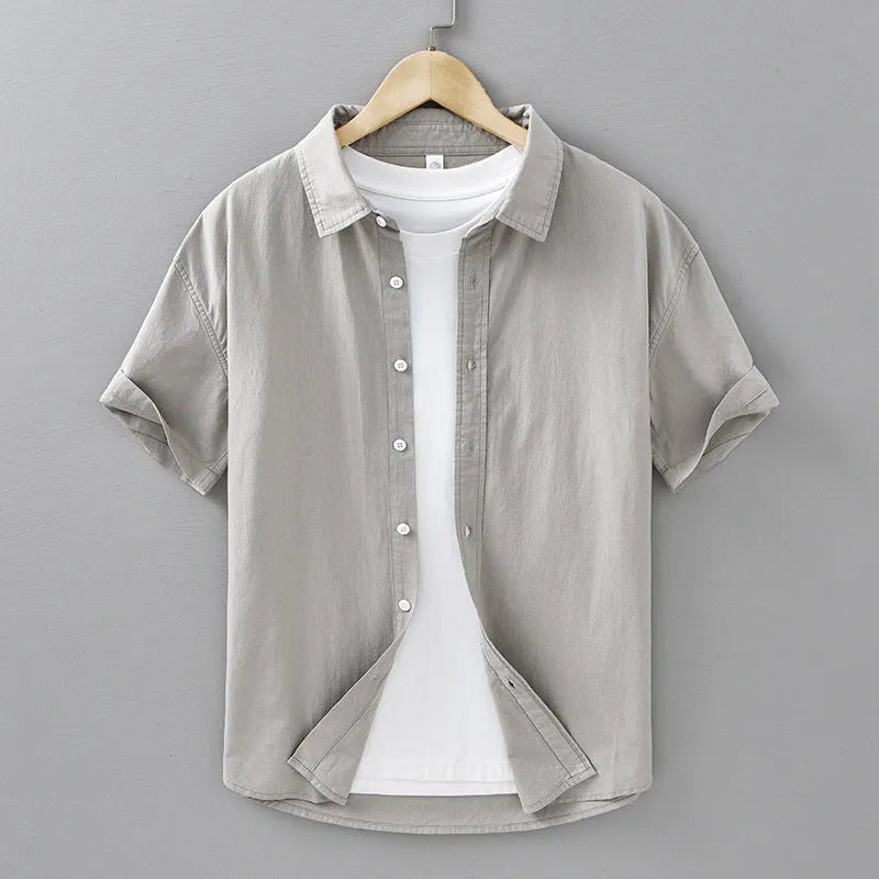 Man wearing a light grey loose-fitting short-sleeved cotton cardigan-style shirt.