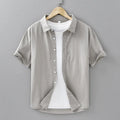Man wearing a light grey loose-fitting short-sleeved cotton cardigan-style shirt.