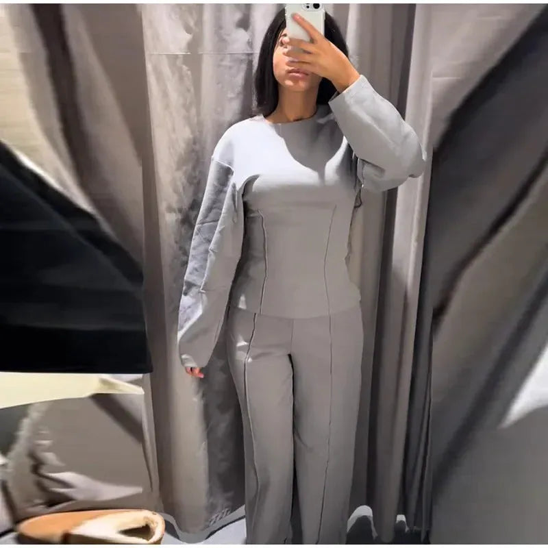 Women's black polar fleece suit set with long sleeve pleated top and wide leg trousers on a hanger.