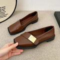 Women's beige square-toe flat shoes with a metal buckle and low rubber sole.