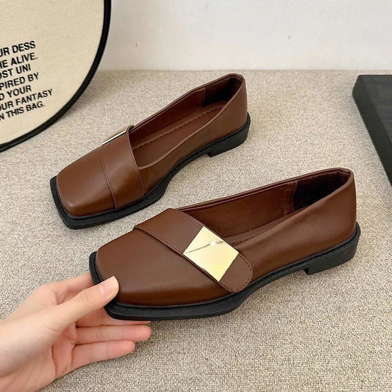 Women's beige square-toe flat shoes with a metal buckle and low rubber sole.