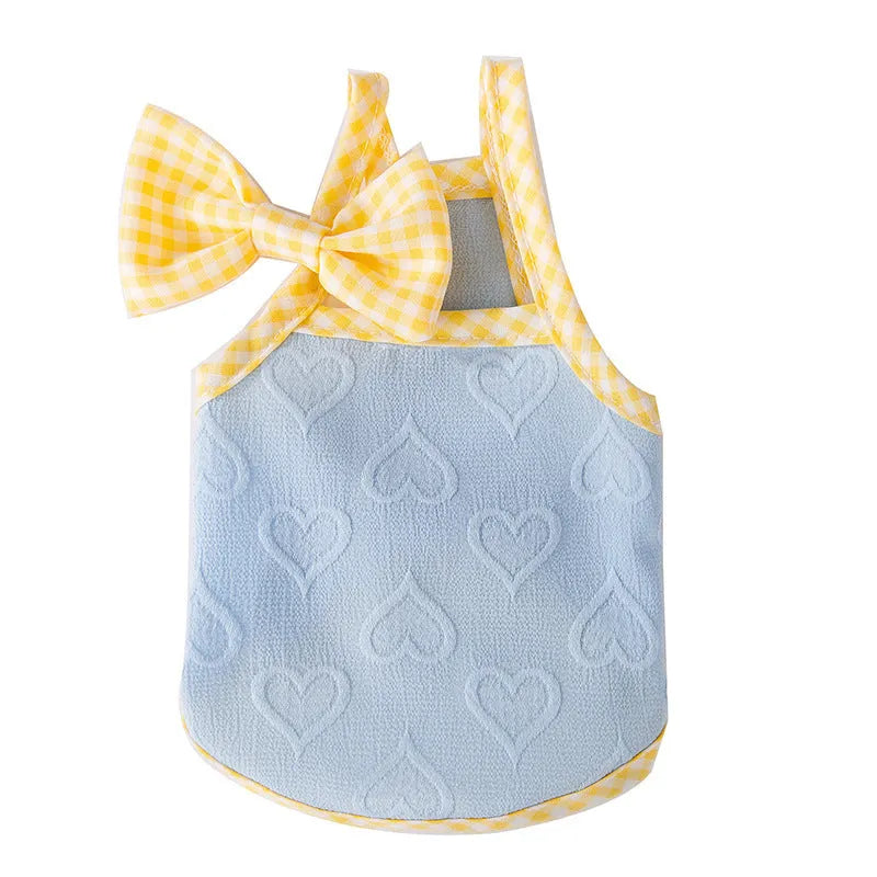 Small dog wearing a blue vest with a heart relief texture and white bow suspenders.