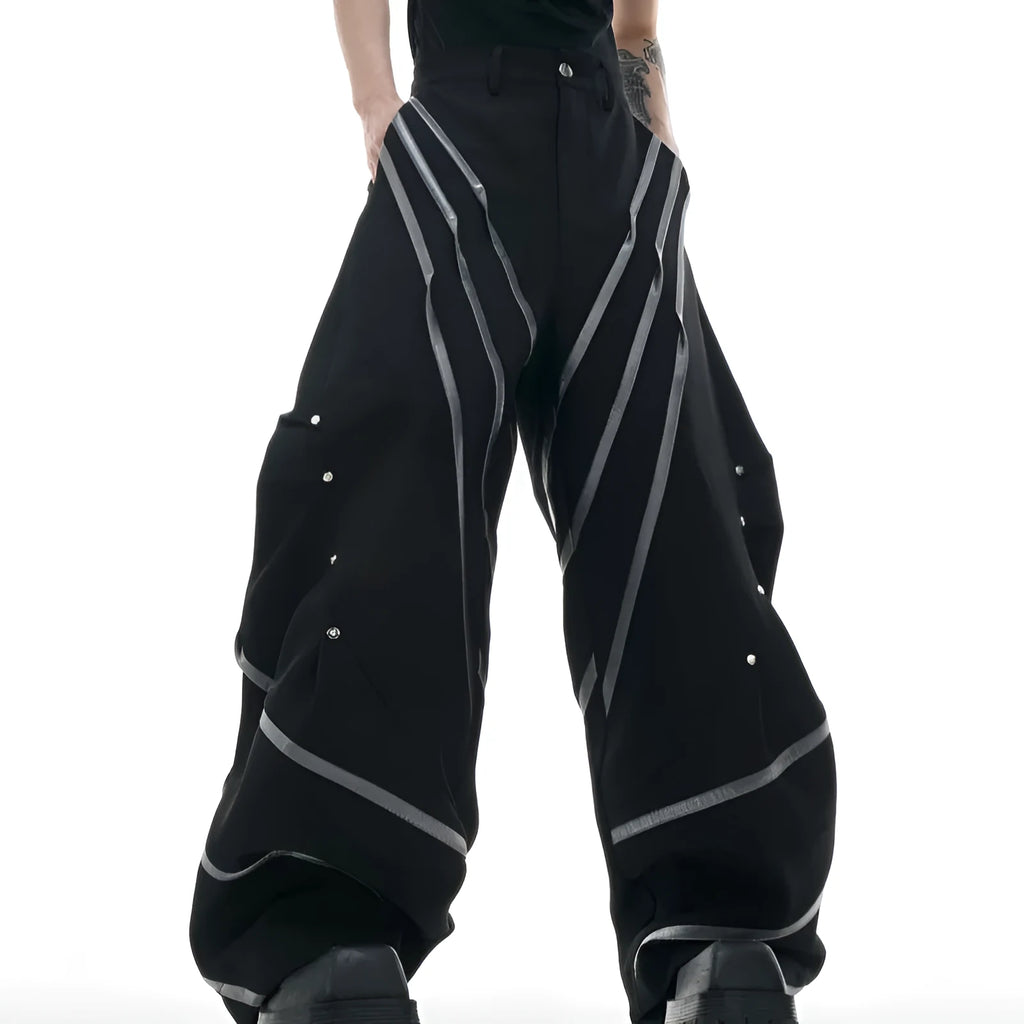 Men's black trousers with metal rivet stripes and pleated detail on the leg.