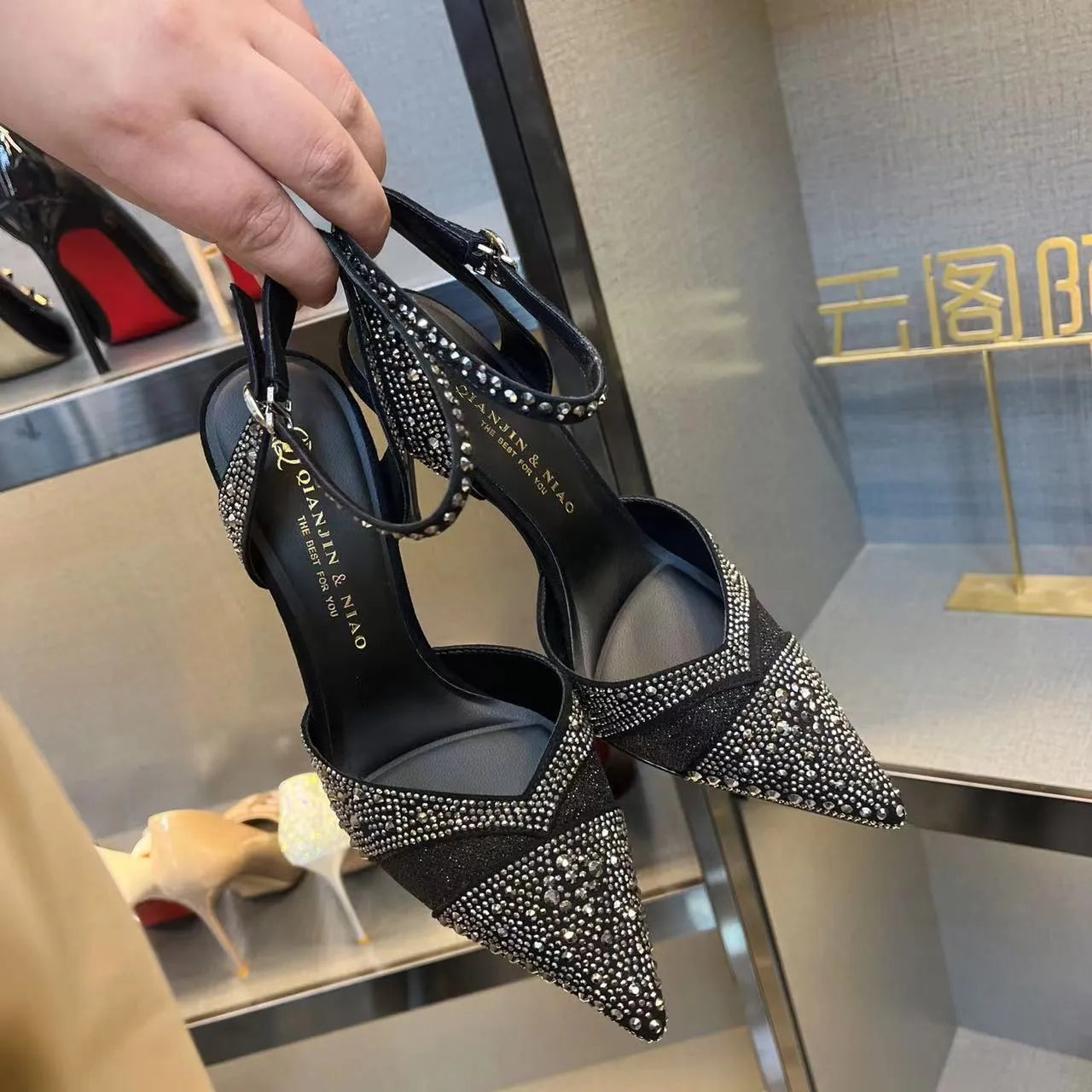 A pair of women's black hollow high heels with a red sole, stiletto heel, and pointed toe.