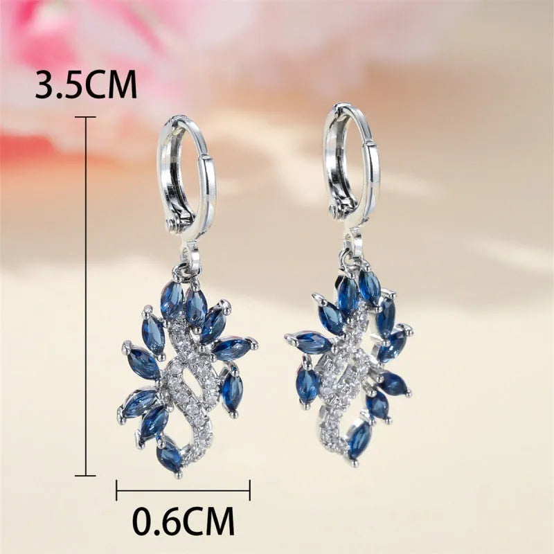 A pair of platinum sapphire blue alloy drop dangle earrings for women on a plain background.