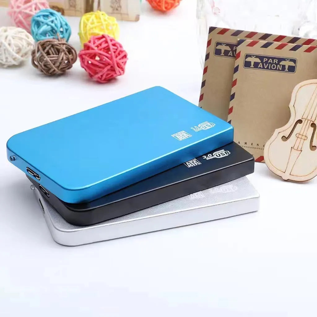 Silver USB 3.0 external solid state hard drive with data cable on a desk.