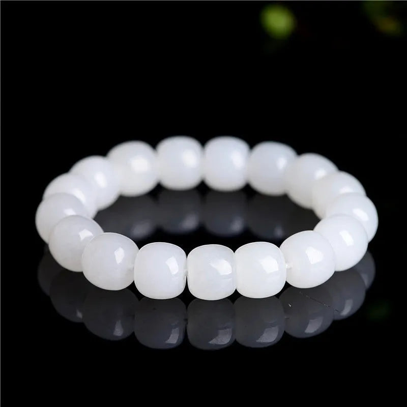White Hetian jade barrel bead bracelet for men and women on a wooden surface.