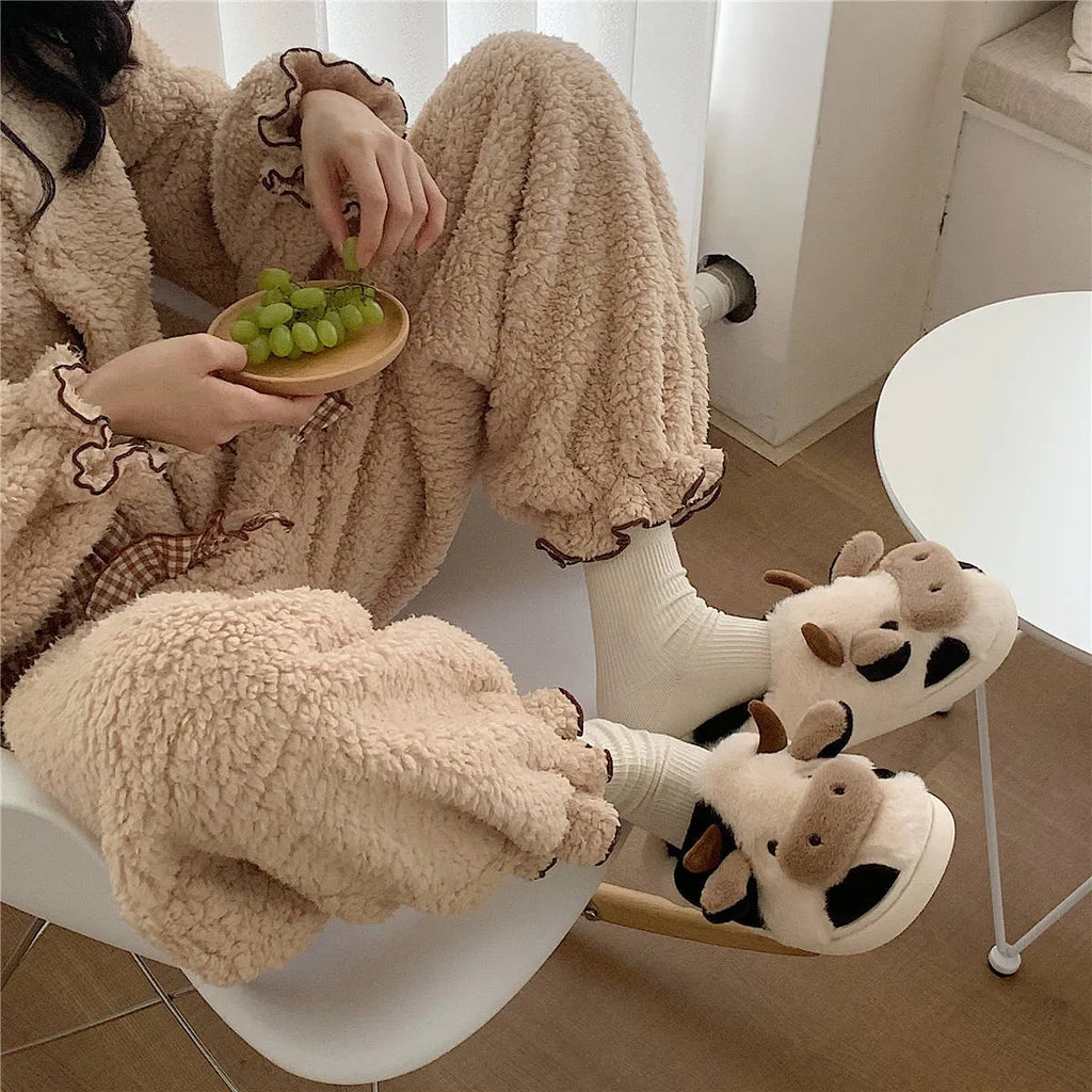 White women's cow pattern slippers made of soft faux fur with textured anti-slip soles.