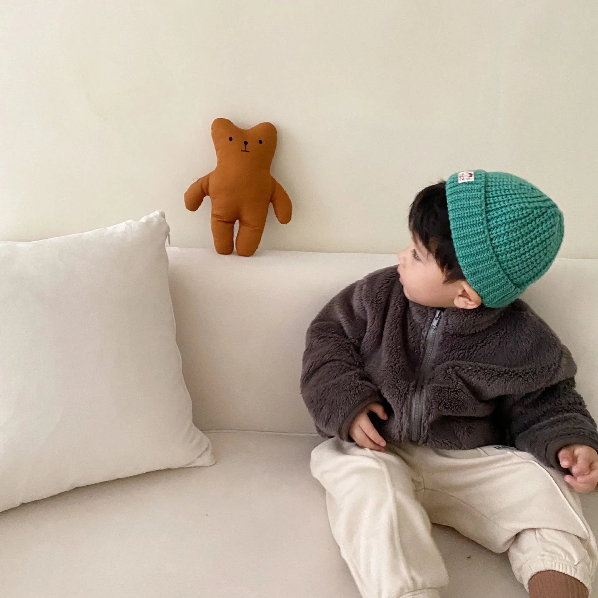 A child's blue sherpa fleece jacket with a full zip, high collar, and front pockets on a hanger.