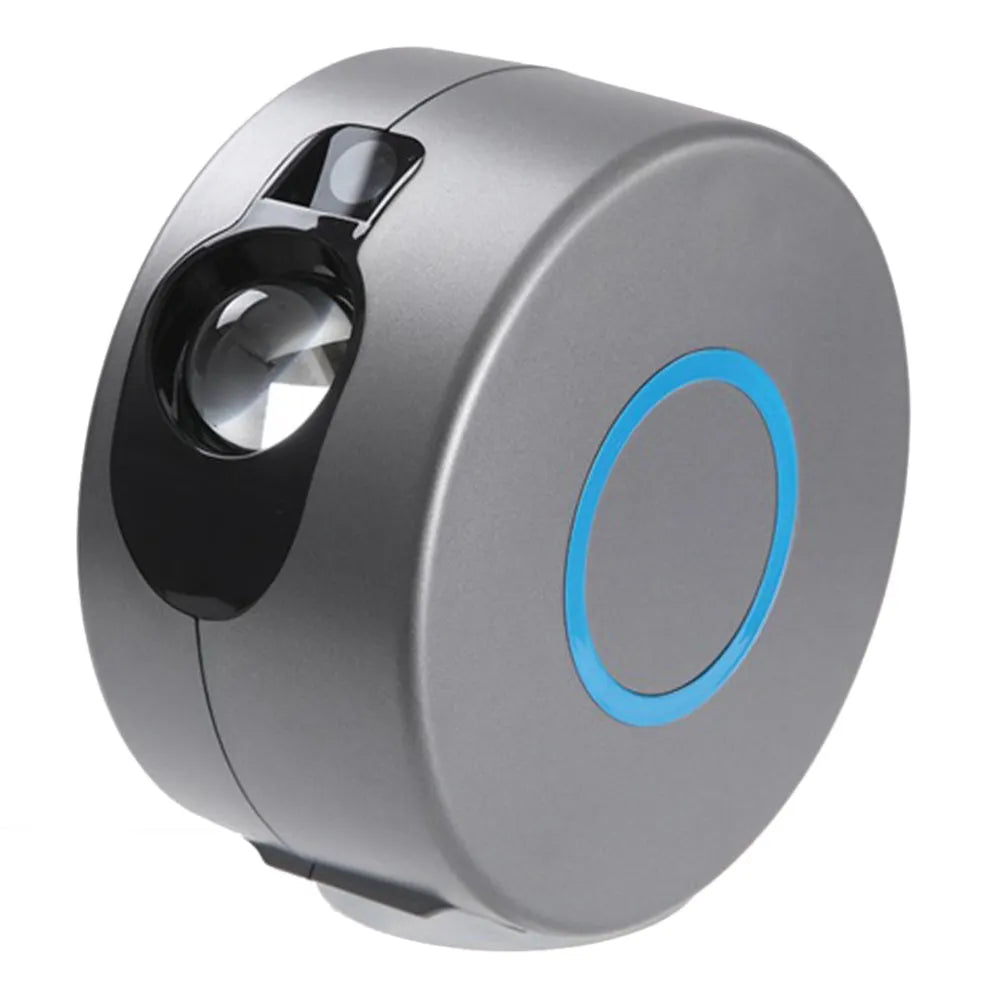Grey starry sky projection lamp with remote control on a table, projecting colourful light dots on a dark wall.