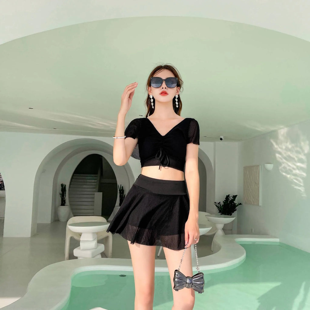 White two-piece women's swimsuit with a skirt bottom, shown alongside black and pink colour options.