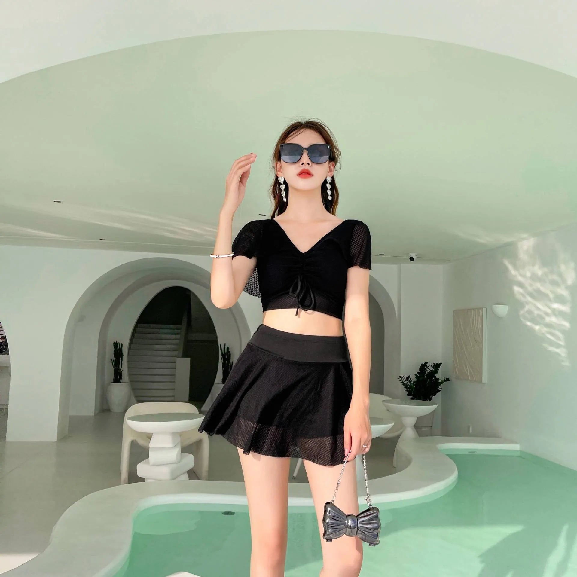 White two-piece women's swimsuit with a skirt bottom, shown alongside black and pink colour options.