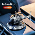 Silver solar-powered metal helicopter car air freshener ornament with spinning blades on a dashboard.