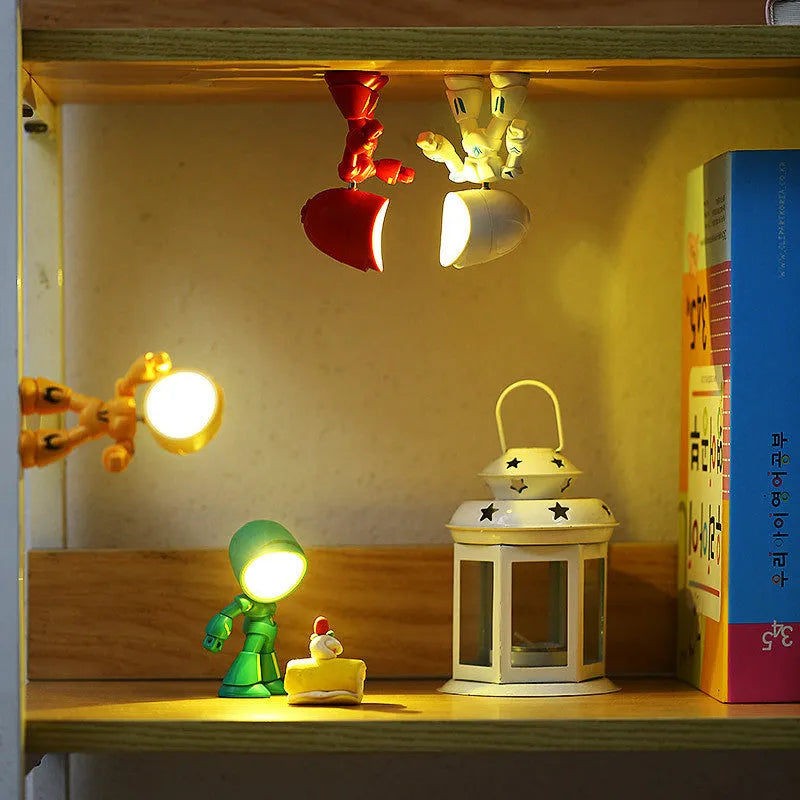 Mini LED hero robot night light with warm glow, adjustable arms, and 360-degree rotating head on a wooden shelf