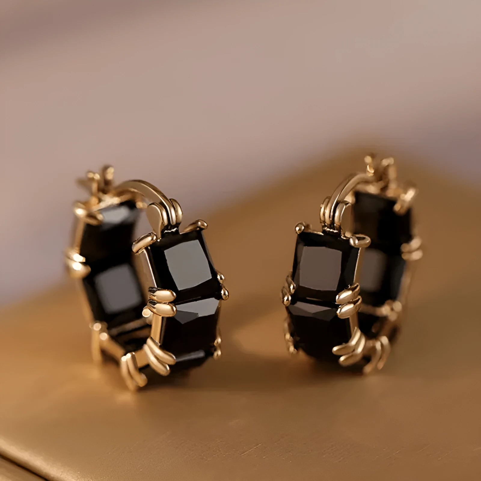 Women's geometric U-shaped gold earrings with round black zircon crystals on white background