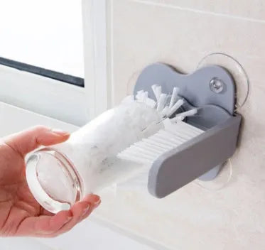 Grey kitchen cleaning brush with two brush heads and suction cups for wall mounting