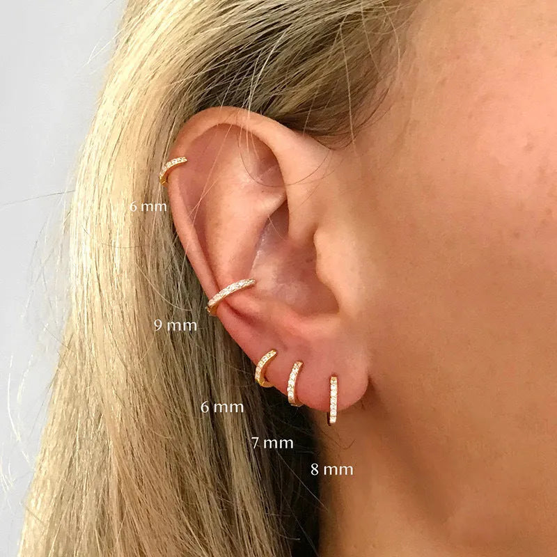Set of three pairs of perforated circle stud earrings in gold, rose gold, and silver colours on a plain background.
