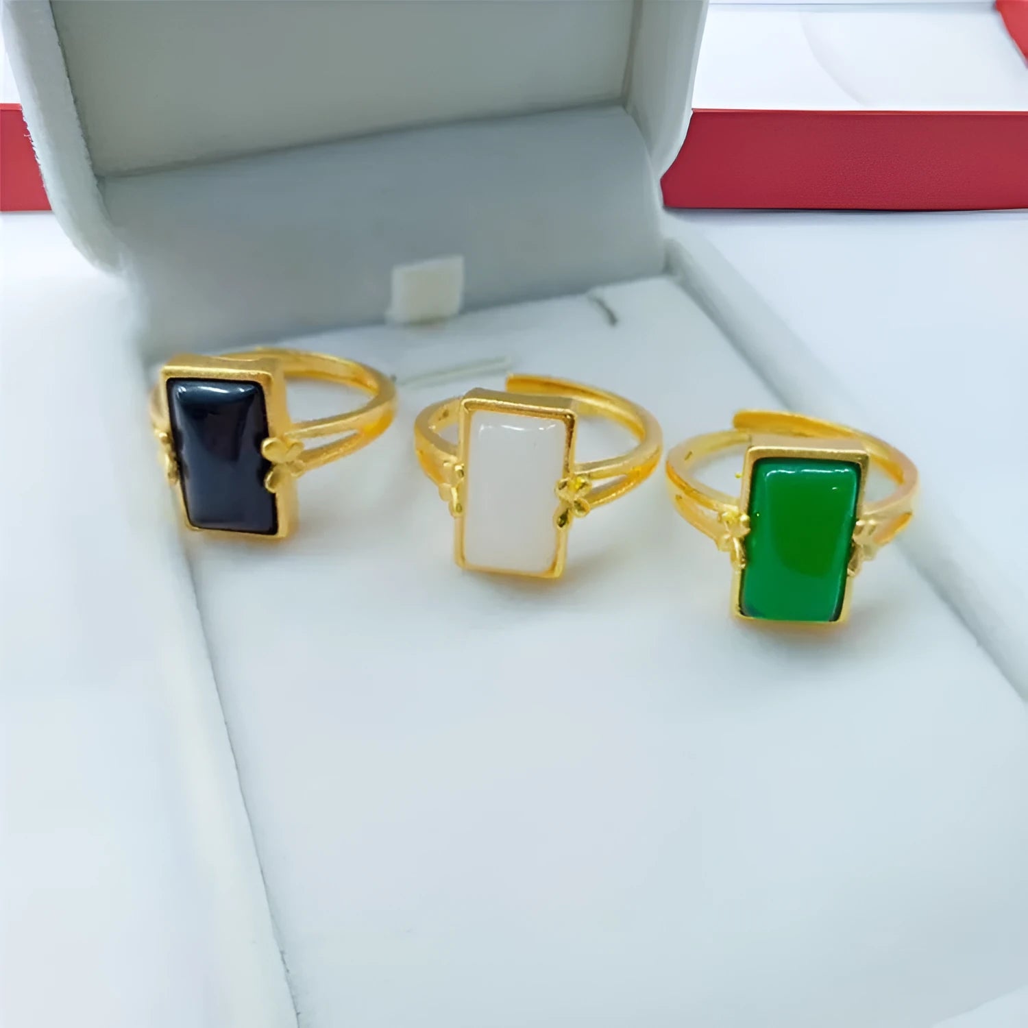 Adjustable gold-plated brass ring with a black artificial gemstone on a neutral background.