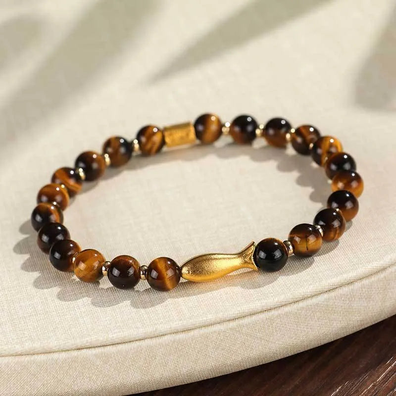 Close-up of a women's bracelet with small fish-shaped Tiger Eye stone beads in yellow, red, or gold colours.
