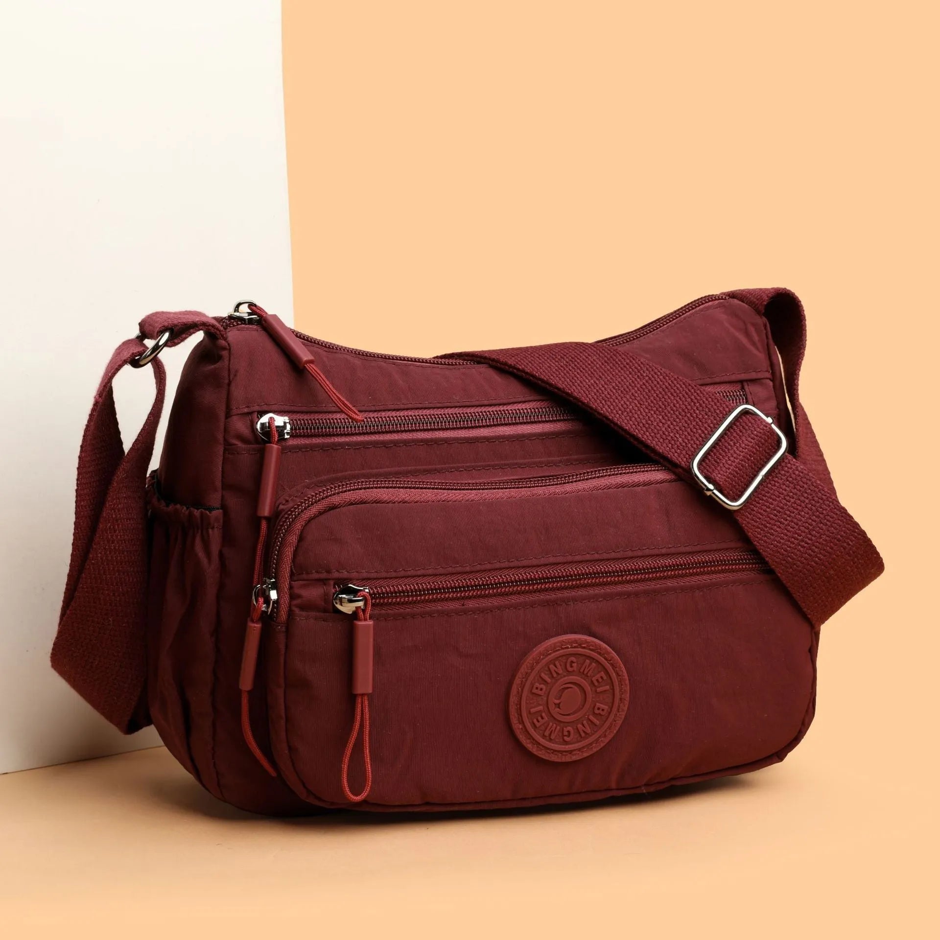 Grey water-repellent nylon crossbody bag showing front three-dimensional pocket and adjustable shoulder strap.