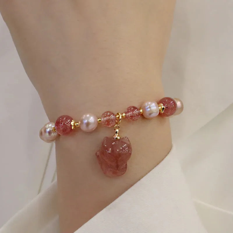 Light pink women's bracelet with freshwater pearls, strawberry quartz beads, and a silver fox charm on a white background.