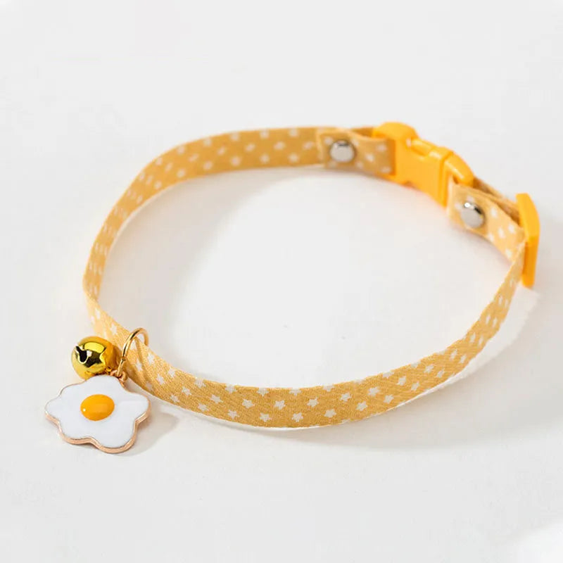 Adjustable green cat collar with a silver bell and pink bow tie on a white background.