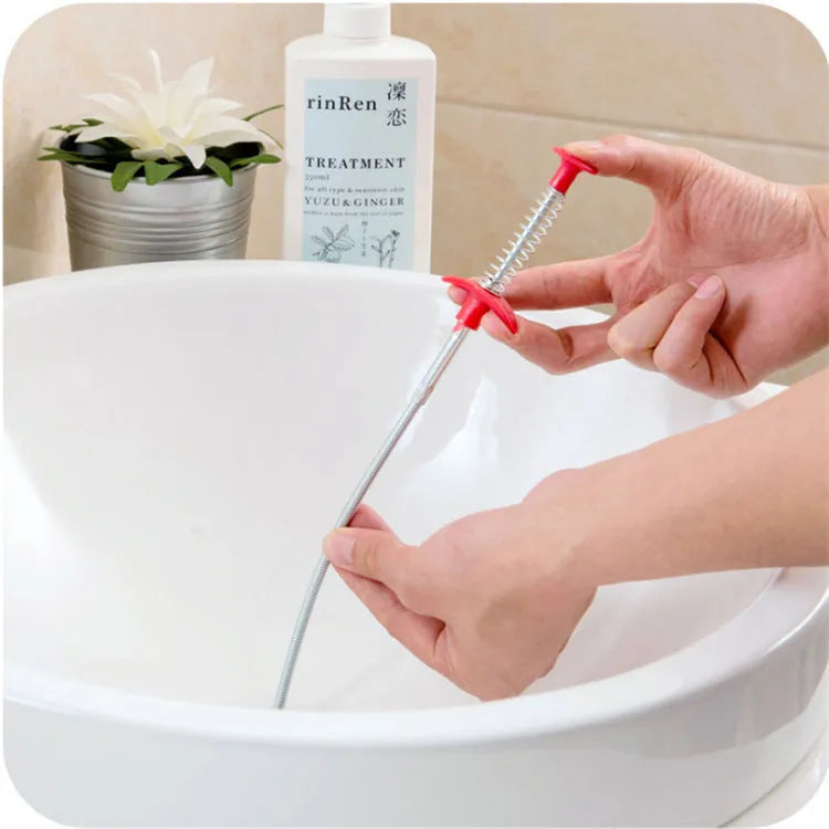 Black sewer dredge spring drain unclogging tool with PP handle next to a kitchen sink