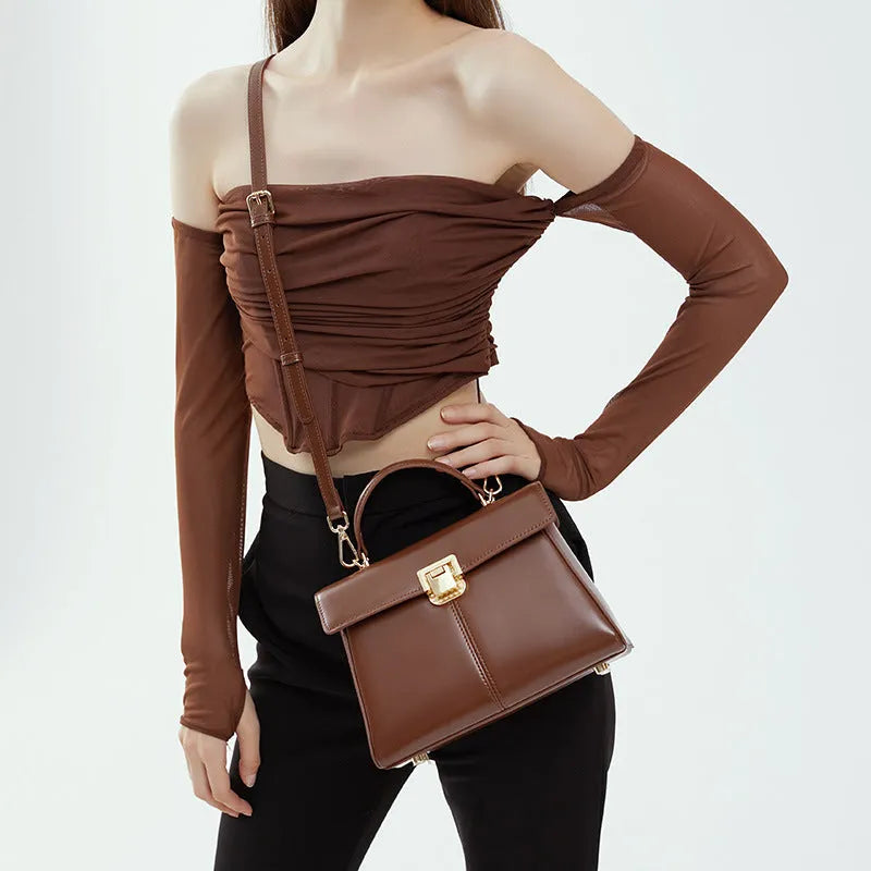 Black genuine leather women's shoulder bag with clasp closure and adjustable strap.