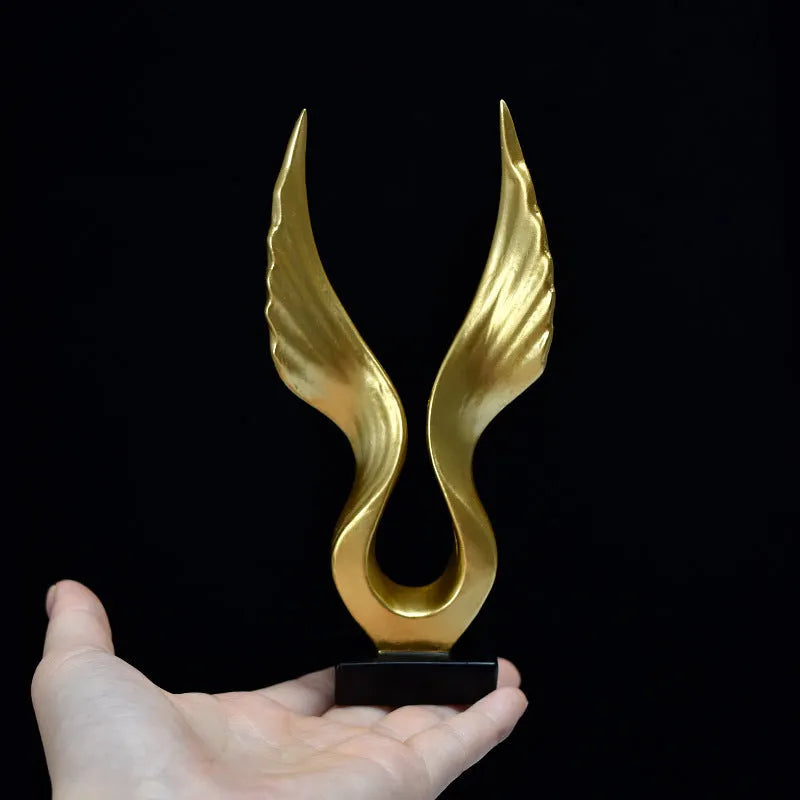 Mini synthetic resin decoration in silver and gold angel wing style on a shelf