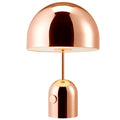 Modern mushroom table lamp with metal base in rose gold finish on a wooden table.