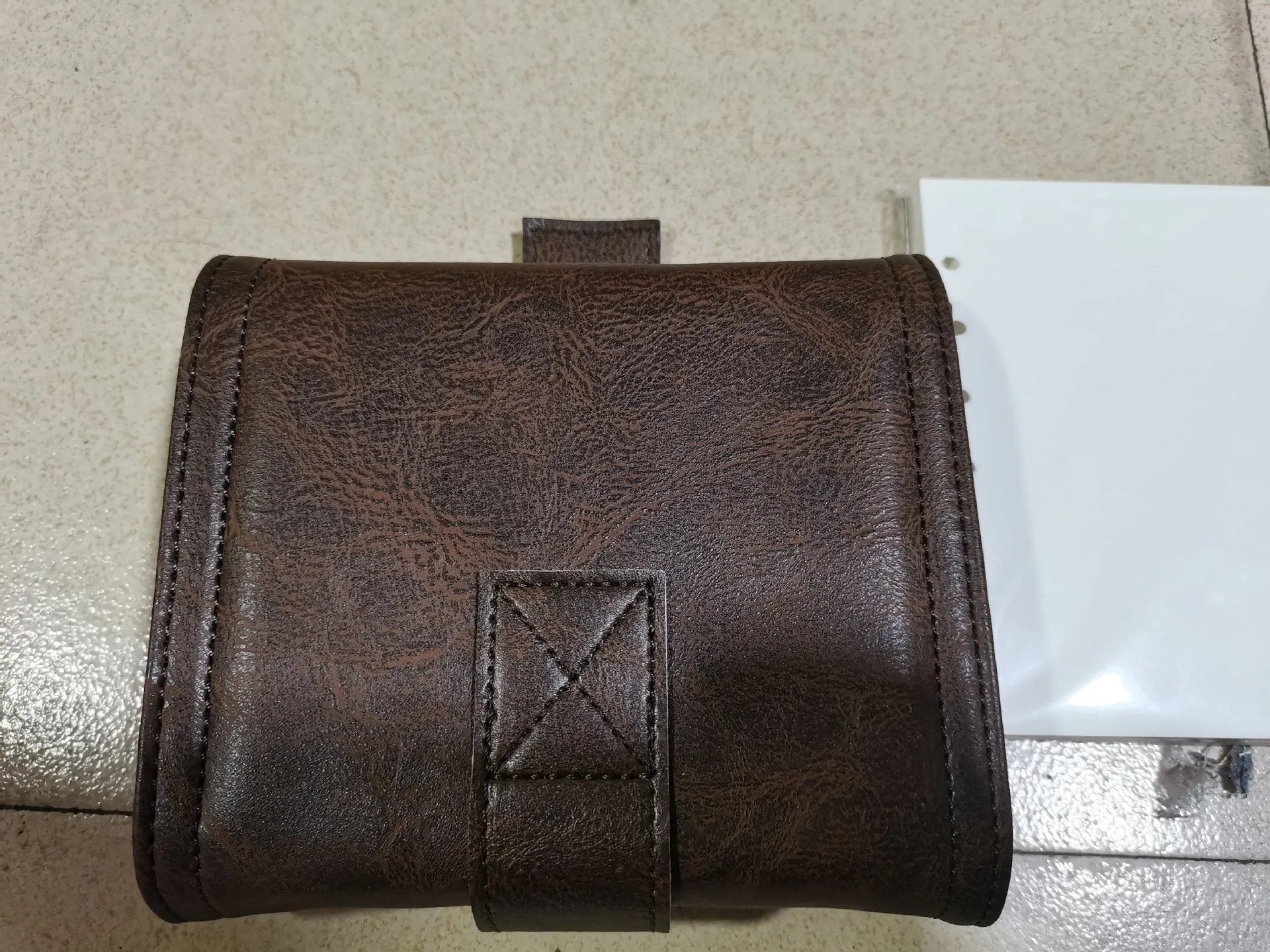 Brown A7 retro notebook with buckle closure showing loose-leaf binding and raw wood pulp paper