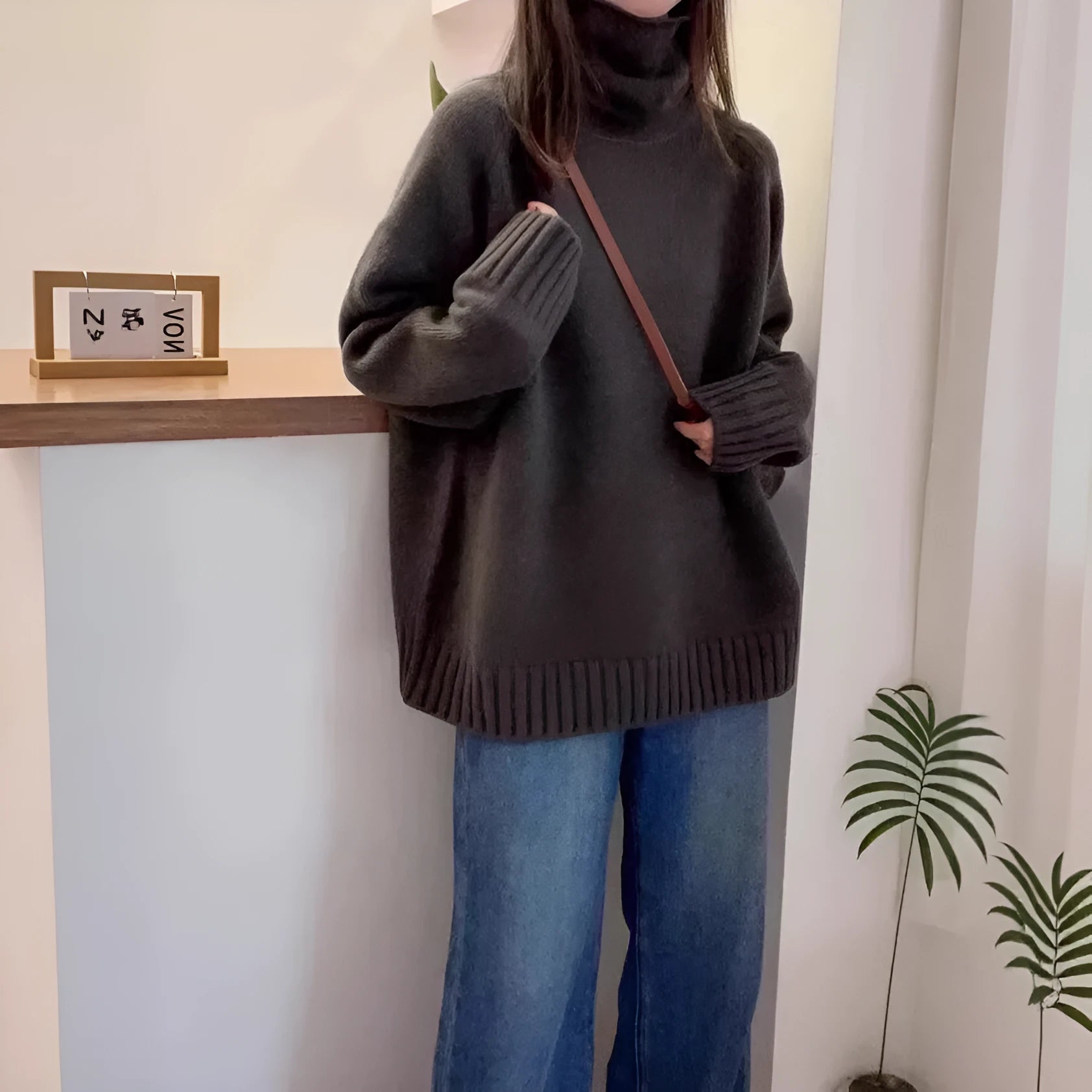 Women's loose grey turtleneck sweater with thick textured pile collar, casual style.