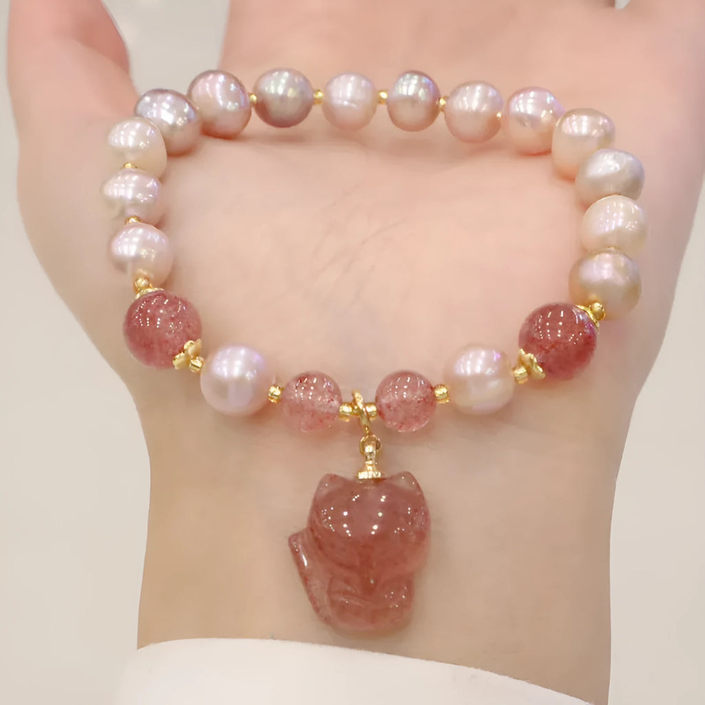 Light pink women's bracelet with freshwater pearls, strawberry quartz beads, and a silver fox charm on a white background.