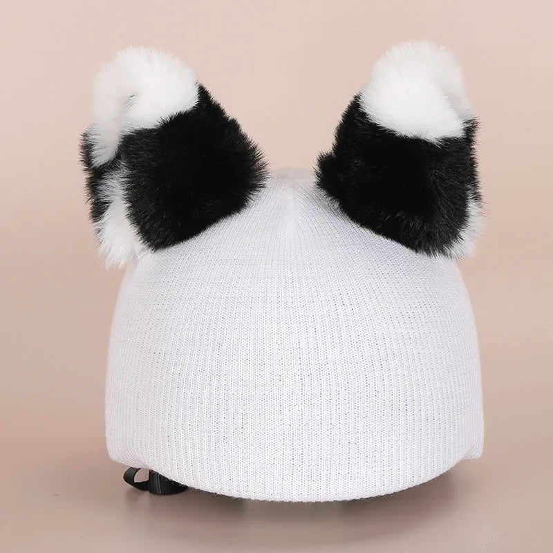 A soft plush cartoon character cover placed over a ski helmet on a snowy background.