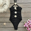 Women's black hollow-out tube top one-piece swimsuit with matching high-waist short skirt laid flat.